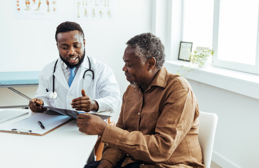 Older male patient speaks with a male doctor