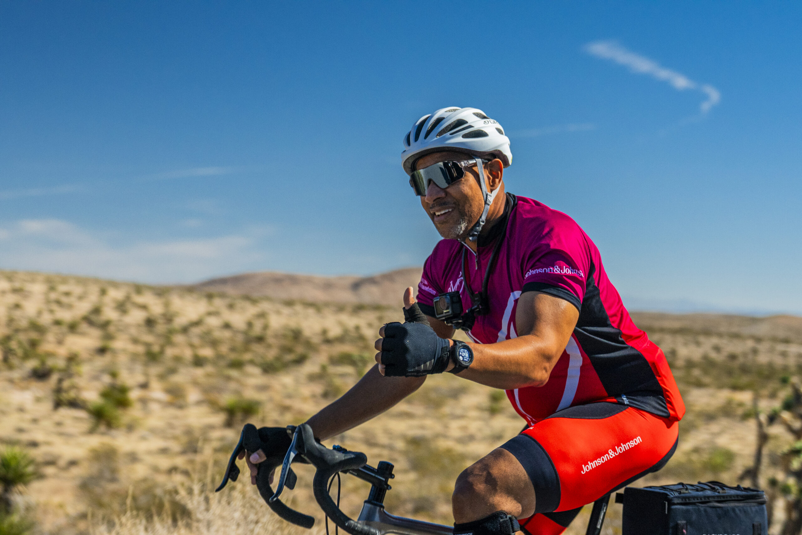 Mike Johnson gives a thumbs up while riding his bike through the desert during Road to Victories.
