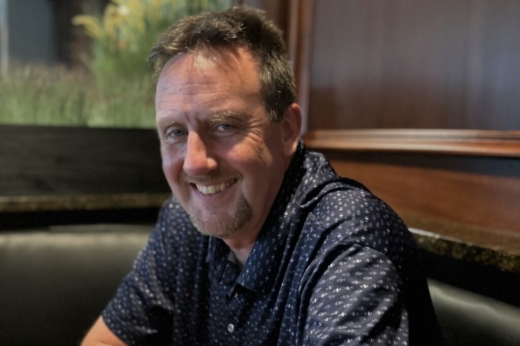 a photo of MMRF Philadelphia Walk Spirit of Hope honoree Gary Brown smiling at the camera sitting in a booth